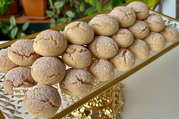 Tarçın ve pudra şekeri serpilmiş, çatlak yüzeyli minik kurabiyeler